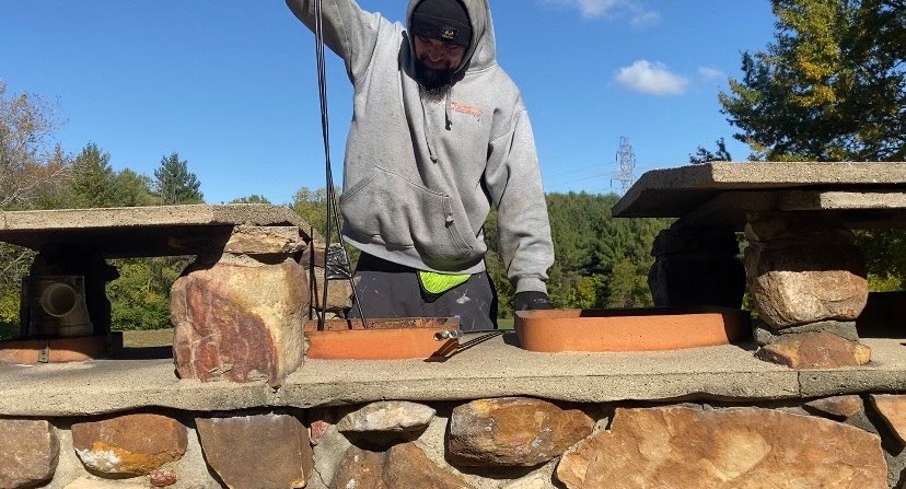Technician performing professional chimney cleaning inside residential fireplace